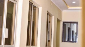 A hallway with a modern ceiling design, large windows, and a neutral color palette. - Rovers Place Hotel  (Ahero)