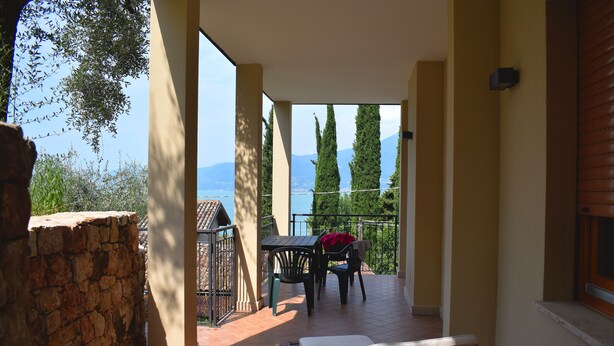 Ein Balkon mit Tisch und Stühlen, der einen schönen Blick auf Berge und ein Gewässer bietet.