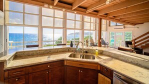 A kitchen with a large island, wooden cabinets, and a view of the ocean.