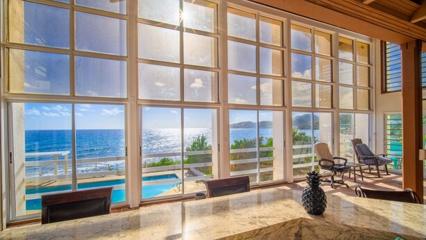A spacious room with large windows overlooking a pool and ocean.
