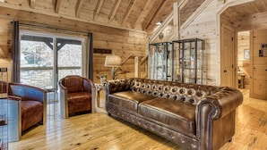 A wooden interior with a leather sofa, a glass cabinet, and a ceiling fan.