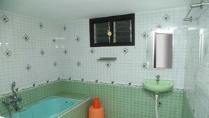 A bathroom with a bathtub, a sink, and a window. -  LA FLORA RESORTS YERCAUD (Yercaud)