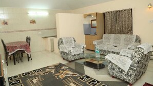 A living room with two patterned sofas, a glass coffee table, a dining table with chairs, and a patterned rug. -  LA FLORA RESORTS YERCAUD (Yercaud)