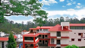 A multi-story building with red-tiled roofs and balconies, surrounded by greenery and trees. -  LA FLORA RESORTS YERCAUD (Yercaud)