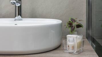 A bathroom with a white sink, a modern faucet, and a small potted plant.