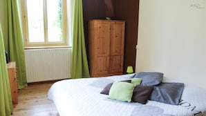 Ein Schlafzimmer mit einem Bett, einem Holzschrank und einem Fenster mit Vorhängen.