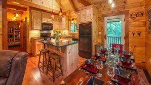 L’intérieur d’une cabane en rondins comprend une cuisine, un coin repas et une grande fenêtre.