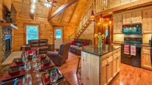 L’intérieur d’une cabane en rondins comprend un coin repas, un salon, une cuisine et un escalier.