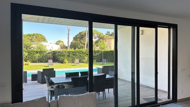 Un salon moderne doté d’une porte-fenêtre coulissante donnant accès à un espace piscine.