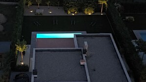 Vue aérienne d’un bâtiment moderne doté d’un toit plat, d’un patio couvert et d’un parking où sont garées deux voitures.