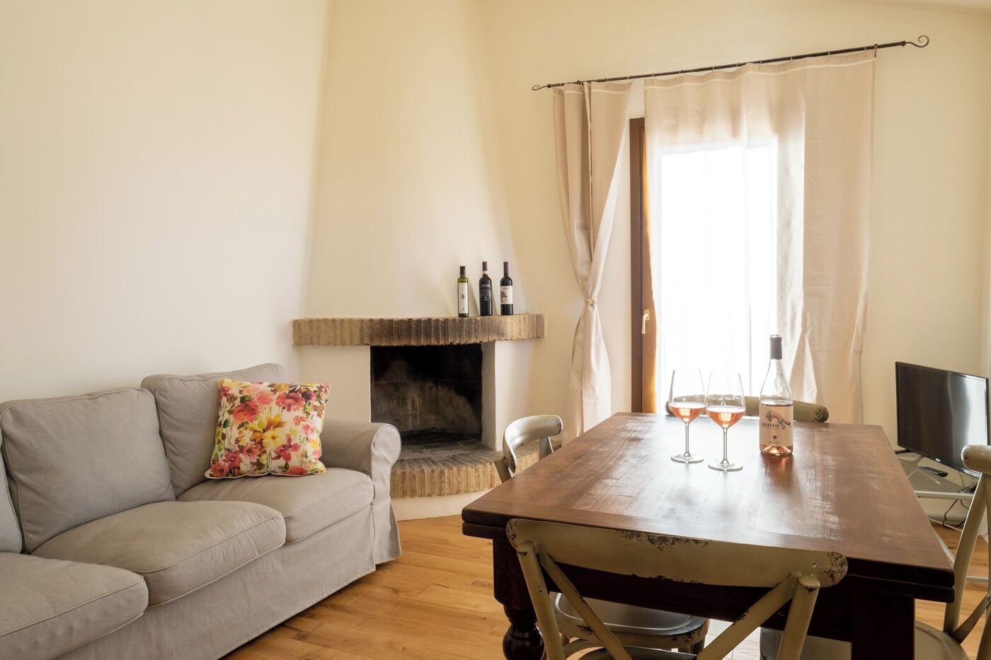 Una sala de estar acogedora con chimenea, una mesa de comedor de madera y un sofá con un cojín floral.