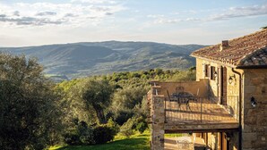 Un bâtiment en pierre doté d’une terrasse offrant une vue sur un paysage montagneux.