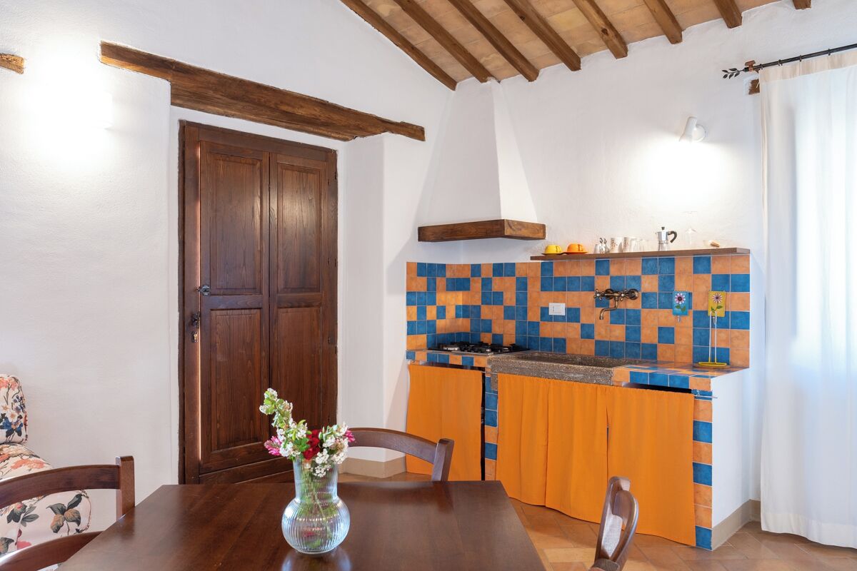 A kitchen with a tiled backsplash, wooden cabinets, and a dining table with chairs.