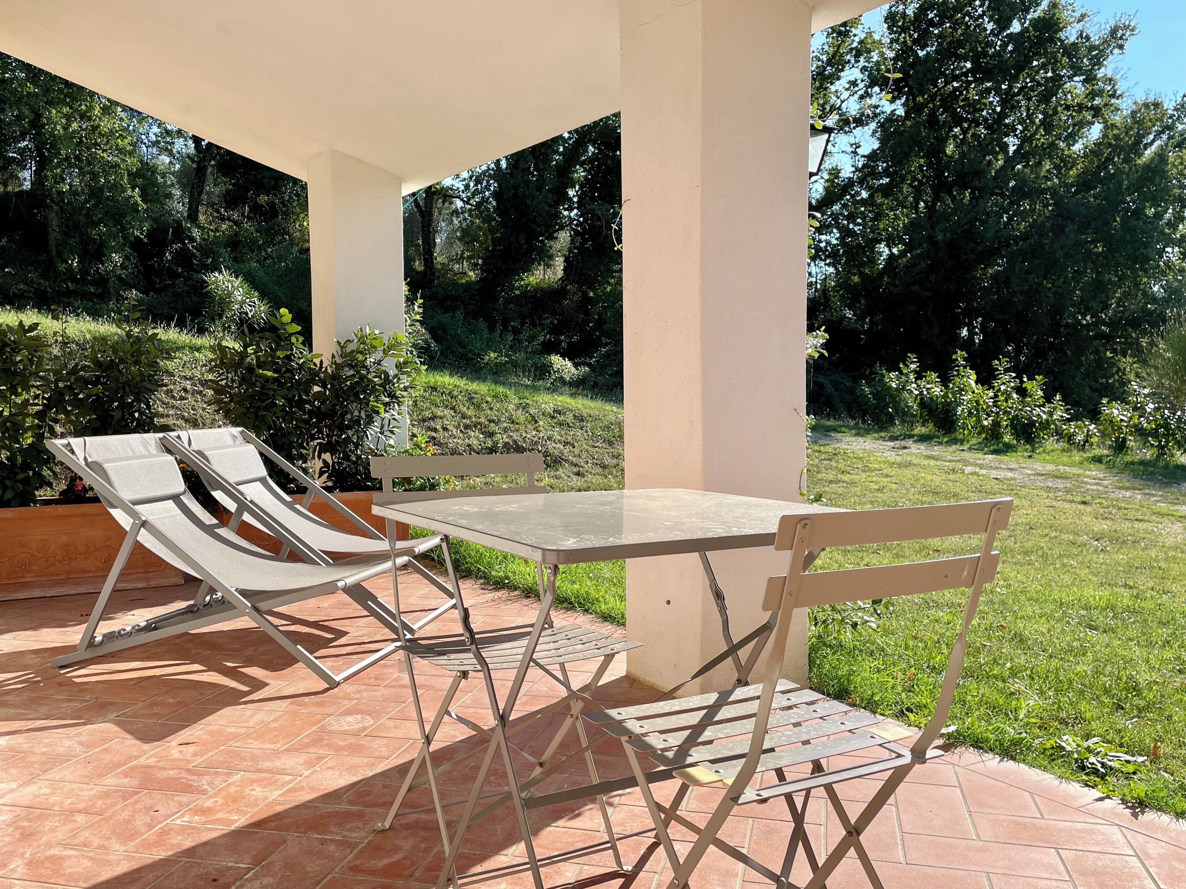 A patio with a table and two lounge chairs.