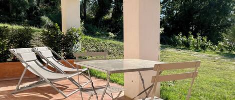 A patio with a table and two lounge chairs.