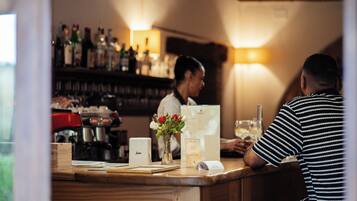 A bar counter with a menu, a coffee machine, and a vase with flowers.