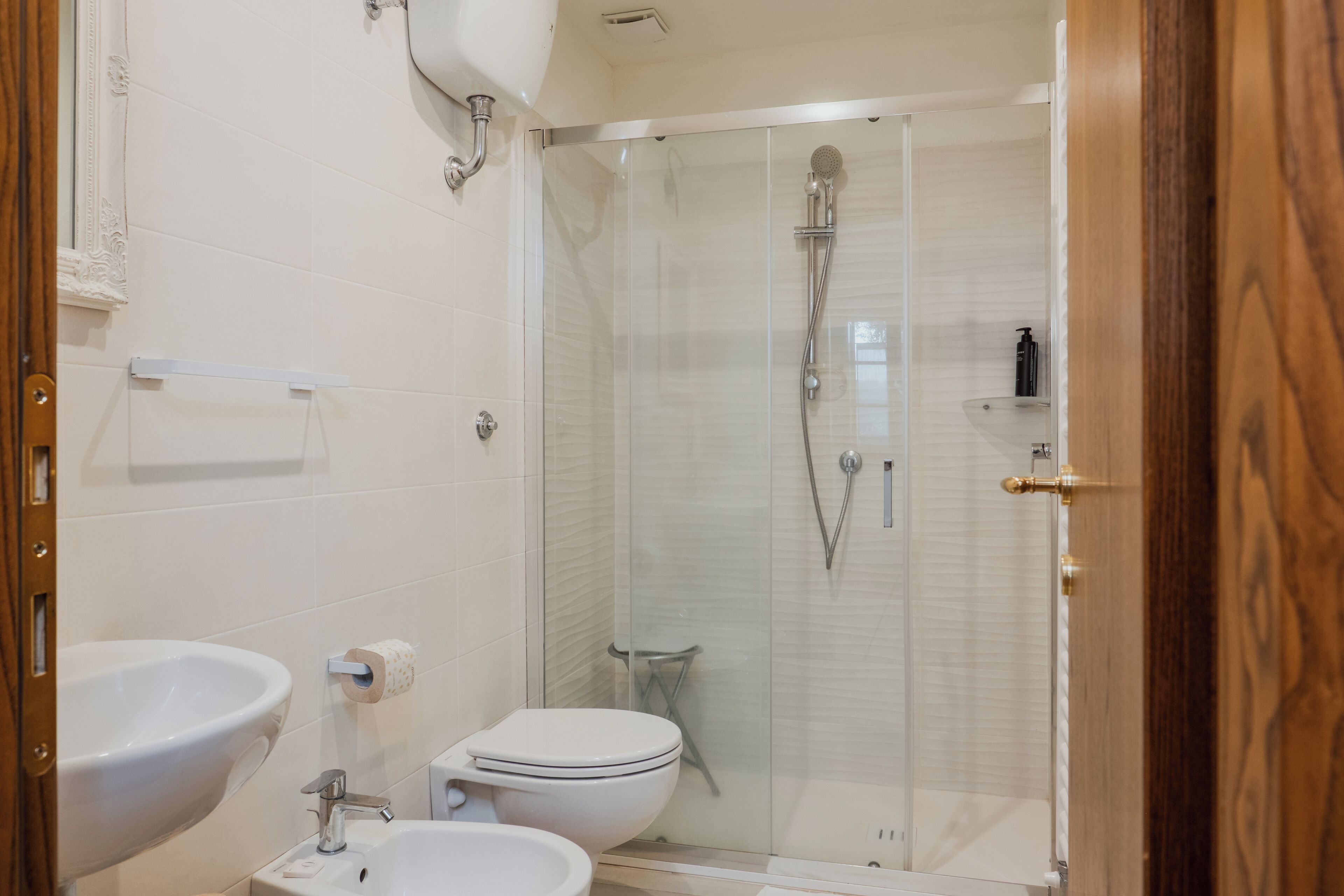 Un bagno con cabina doccia in vetro, un lavandino bianco e un water.