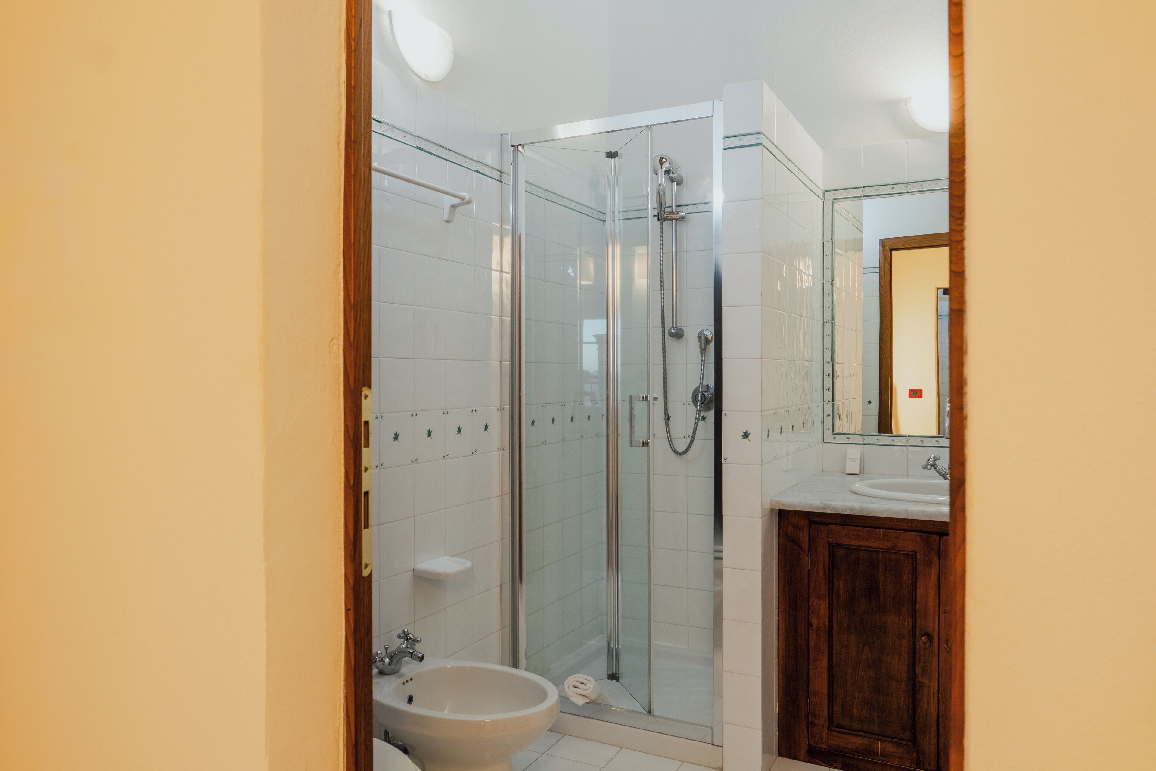 Une salle de bain avec une douche à parois de verre, un lavabo et un meuble en bois.