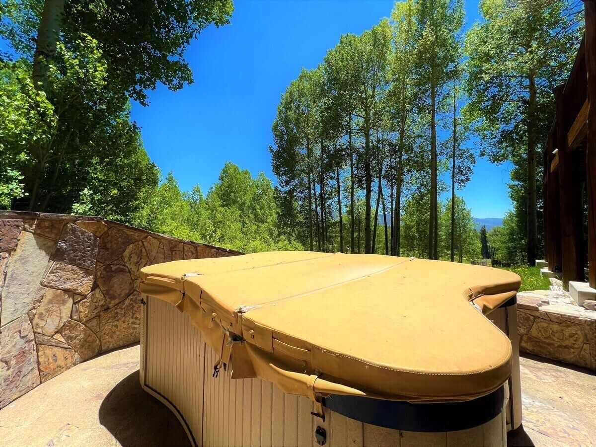 Una banyera d'hidromassatge en un entorn natural amb una paret de pedra i arbres al fons.