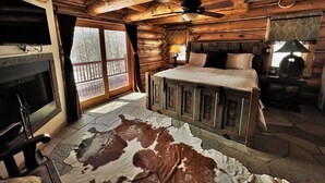 A log cabin room with a bed, a fireplace, and a large window. - Beautiful Log Cabin 3 Miles to Purgatory Ski Resort with Private Hot Tub (Durango)