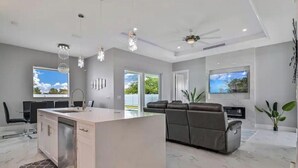 A modern kitchen with a central island, grey walls, and large windows.