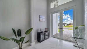 A modern hallway with a marble floor, a glass cabinet, and a potted plant.