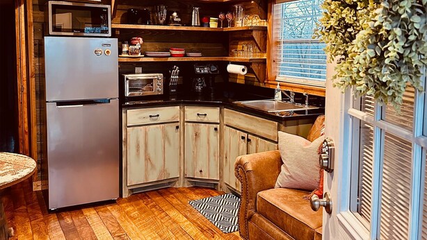 A compact kitchen with wooden cabinetry, a refrigerator, a stove, and a ceiling fan. - Cozy tiny cabin, kitchenette, private pond for fishing, near lake (Ringold)