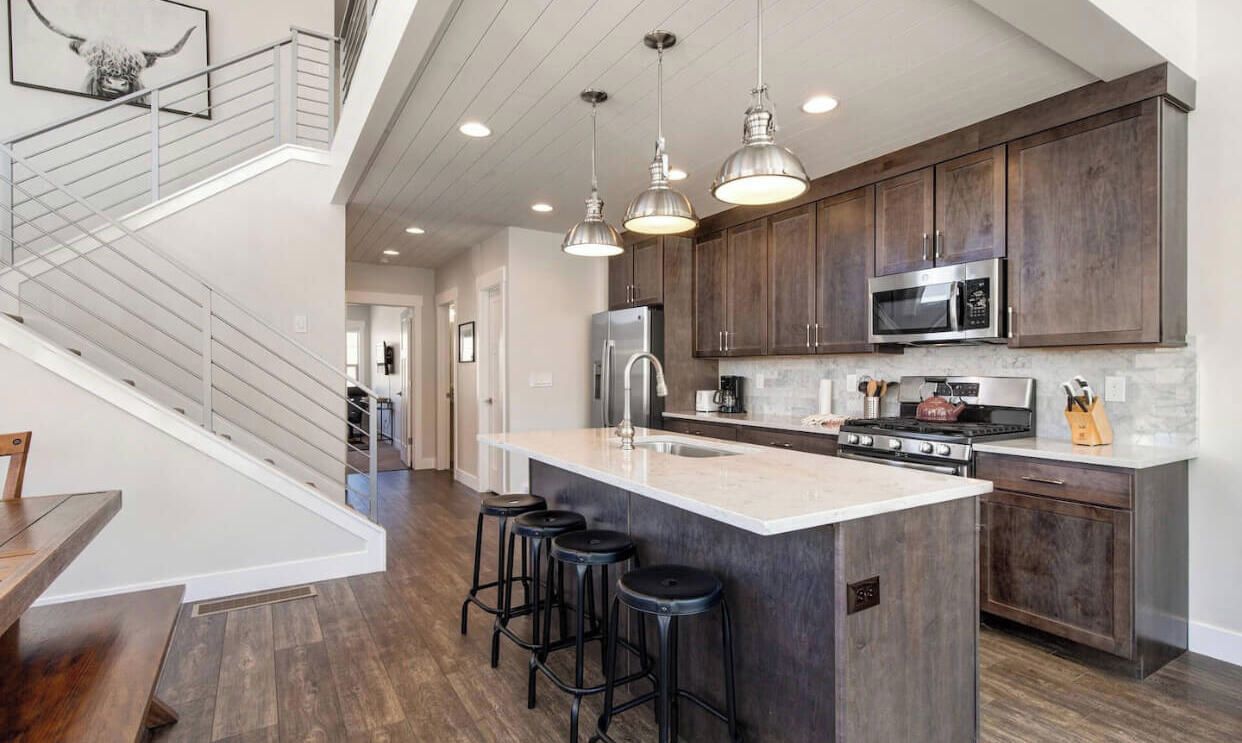 A modern kitchen with a central island, stainless steel appliances, and bar stools.