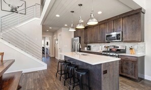 A modern kitchen with a central island, stainless steel appliances, and bar stools. - Moose Mgmt at Wasatch Springs 13804: Free Bus Routes-Garage Parking-Fast WiFi (Park City)