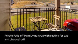 Eine private Terrasse mit Sitzgelegenheit für zwei Personen und einem Holzkohlegrill.