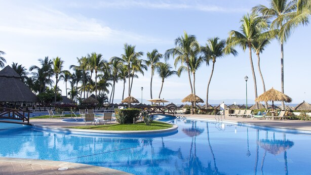 A swimming pool with lounge chairs and palm trees.