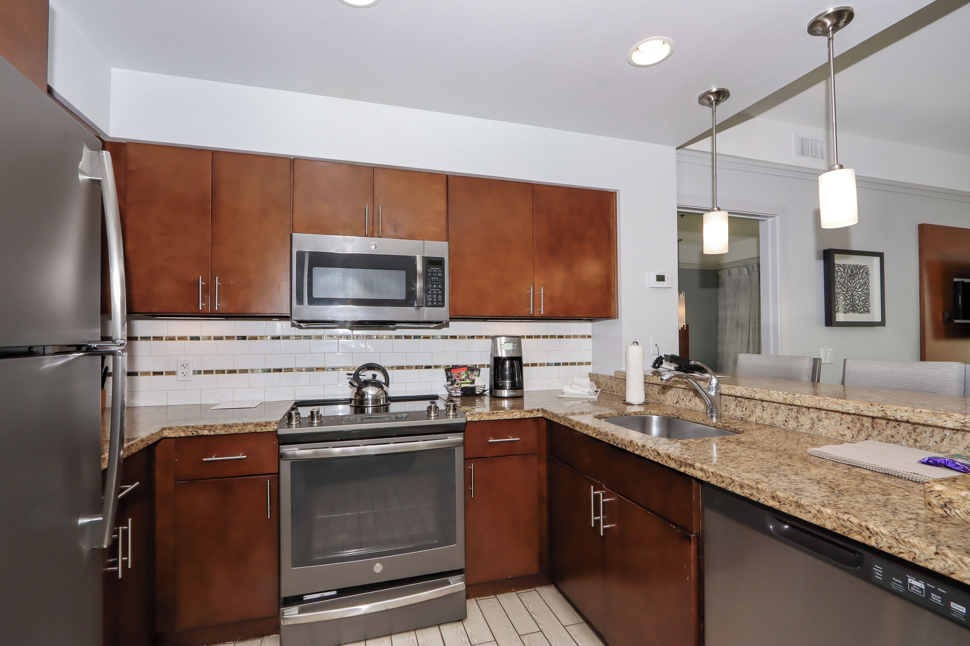 A modern kitchen with stainless steel appliances, granite countertops, and wooden cabinets.
