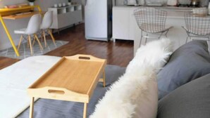 A modern living room with a wooden tray table, a fluffy white pillow, and a kitchen area in the background. - Cozy Studio 7 Palermo Soho/ Balcony/Pool/Sum/AA. (Buenos Aires)