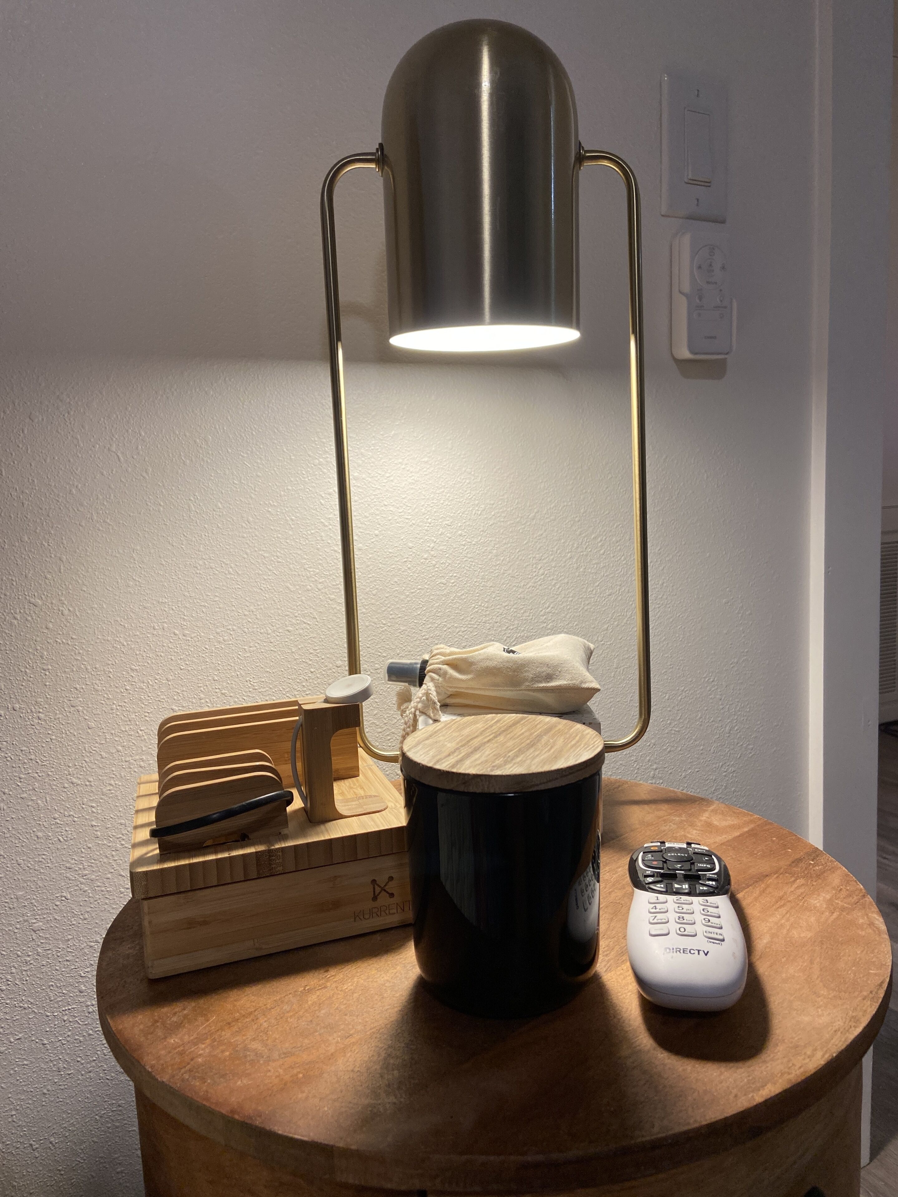 A wooden side table with a black mug, a remote control, and a wooden block with a knife on it.