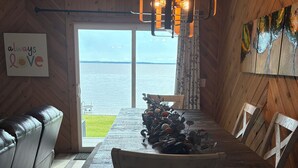Un comedor con una mesa de madera, sillas y vista al mar.