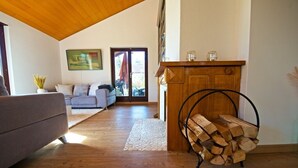 Un salon avec un plafond en bois, un canapé, une cheminée et une vue sur l’extérieur.