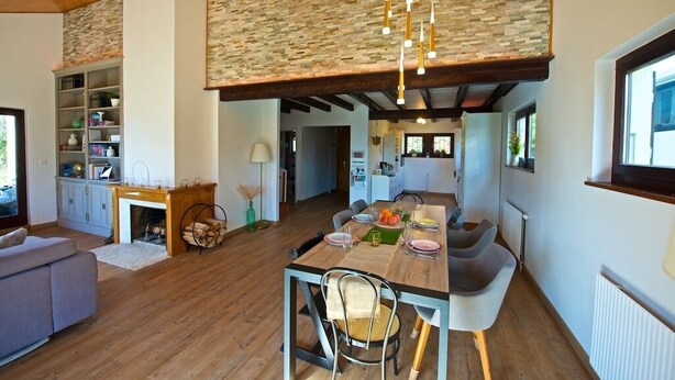 Une cuisine moderne avec un coin repas, un plancher en bois et un mur d’accent en pierre.