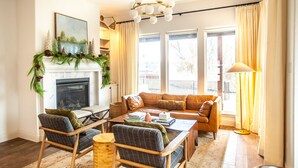 Ein gemütliches Wohnzimmer mit Kamin, einer Couch, zwei Sesseln, einem Couchtisch und einer Lampe.