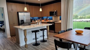 Una cocina moderna con armarios de madera, un refrigerador de acero inoxidable, un microondas y una isla grande con taburetes de bar.