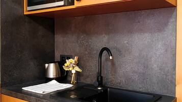 Una cocina con armarios de madera, encimera negra, hervidor de acero inoxidable y grifo negro.