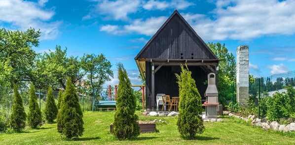 A rustic wooden building with a pitched roof, surrounded by a well-maintained lawn and several coniferous trees. - Jurika Liptov (Bobrovec)