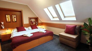 A hotel room with a large bed, a sofa, a desk, and a skylight.