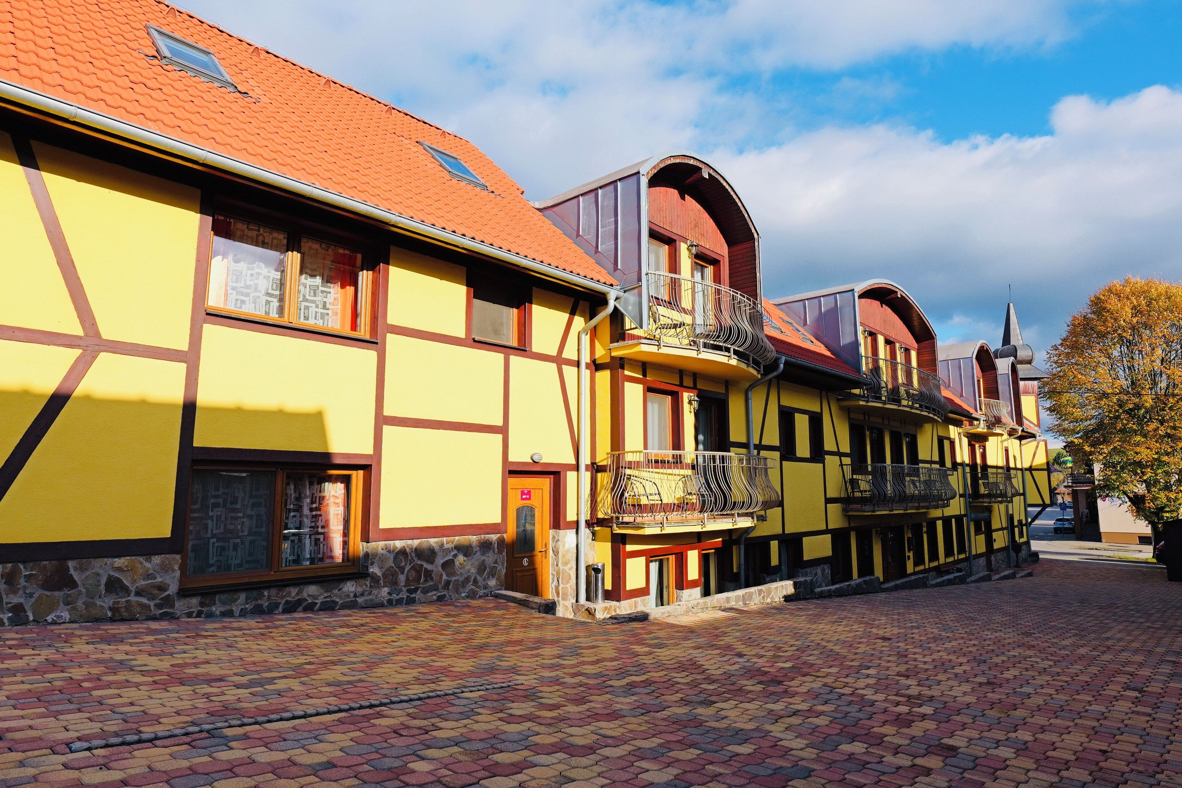 Un edifici europeu tradicional amb façana groga, base de pedra i teulada de rajola vermella.