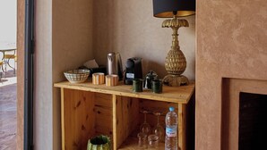 Canto de um quarto com uma estante de madeira contendo um abajur, uma chaleira e uma garrafa.