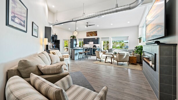 Uma sala de estar moderna com sofá, área de jantar, cozinha e lareira.