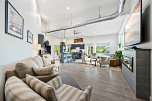 A modern living room with a sofa, dining area, kitchen, and a fireplace.
