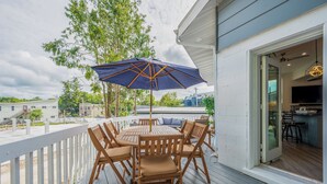 Um deck de madeira com mesa, cadeiras e um guarda-sol, com vista para os arredores.