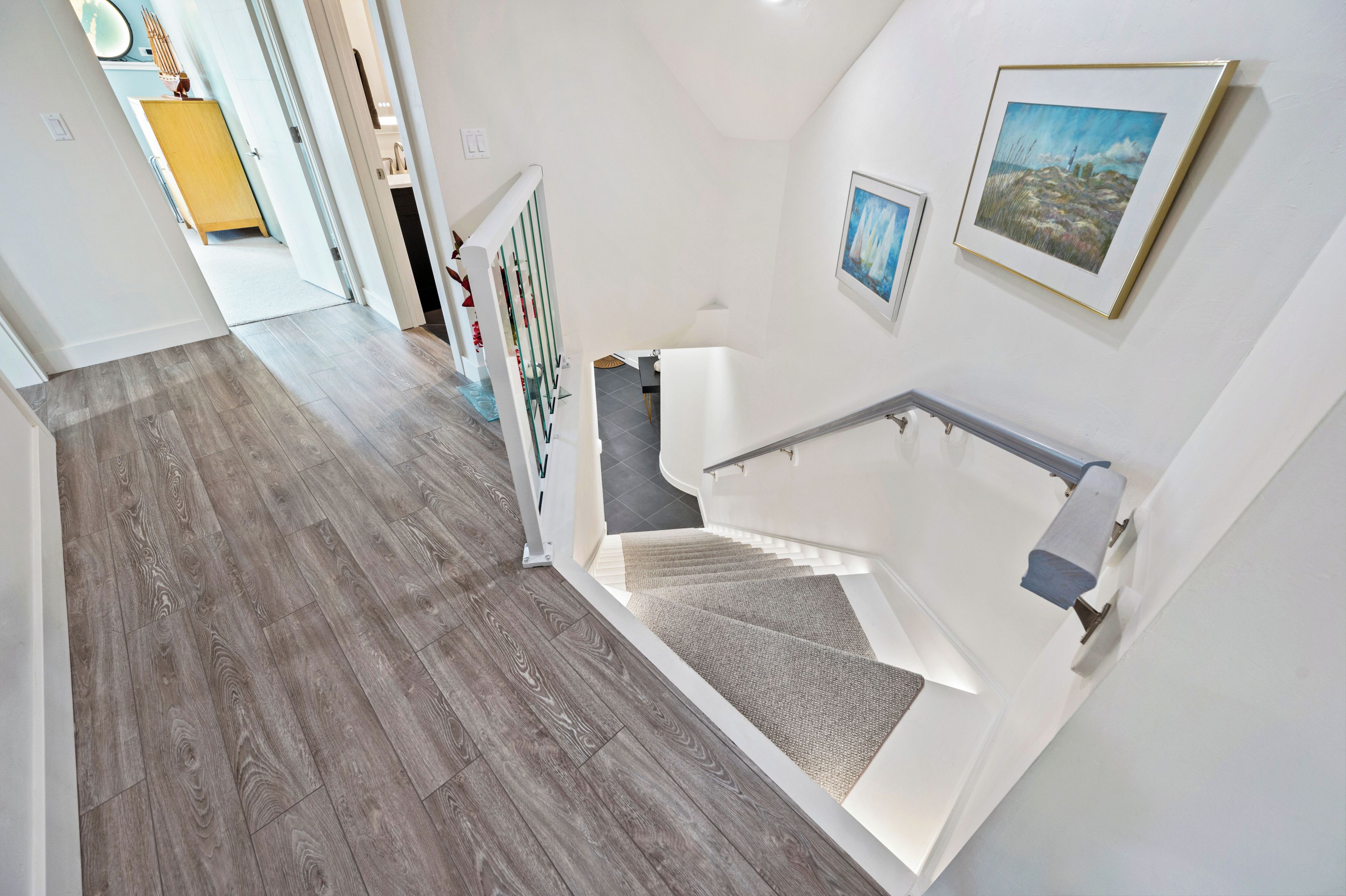 A modern interior with a wooden floor, a staircase with a handrail, and a wall-mounted picture.