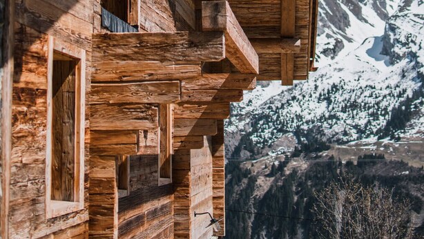 Une cabane en bois dotée d’un balcon donnant sur une chaîne de montagnes enneigées.
