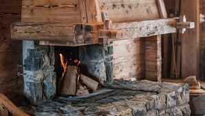 Une cheminée en pierre avec une cheminée en bois et un feu de bois qui crépite à l’intérieur.